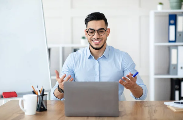 Tutor árabe masculino que lleva a cabo la lección en línea, utilizando el ordenador portátil para la educación a distancia, espacio para el texto en pizarra vacía — Foto de Stock