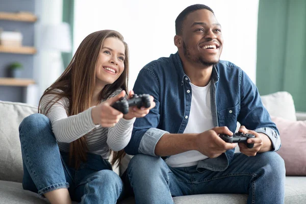 Ocio de fin de semana. alegre pareja mixta jugando video juegos en sala de estar —  Fotos de Stock