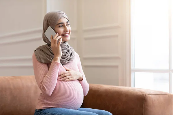 Feliz embarazada musulmana hablando en el teléfono celular en casa — Foto de Stock