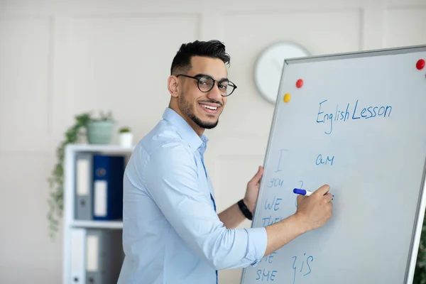 Joven profesor árabe dando clases en línea, explicando nuevo material, escribiendo reglas de inglés en pizarra en la oficina en casa — Foto de Stock
