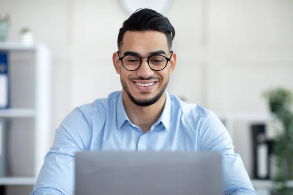Junger arabischer Geschäftsmann mit Laptop arbeitet online und präsentiert sich im modernen Büro — Stockfoto
