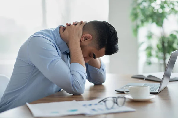 Νεαρός Άραβας με δυνατό πόνο στον αυχένα ή πονοκέφαλο, κουρασμένος από την εργασία σε φορητό υπολογιστή στο σύγχρονο γραφείο, αντιγραφή χώρου — Φωτογραφία Αρχείου