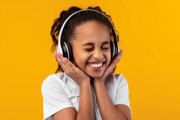 Sorridente giovane ragazza nera in ascolto di musica in cuffia — Foto Stock