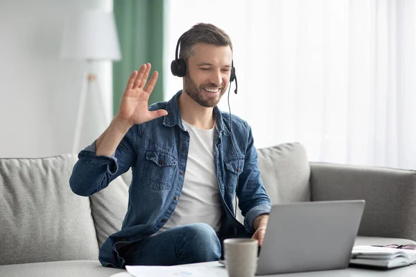Glimlachende man met zakelijke videoconferentie, met behulp van headset en laptop — Stockfoto