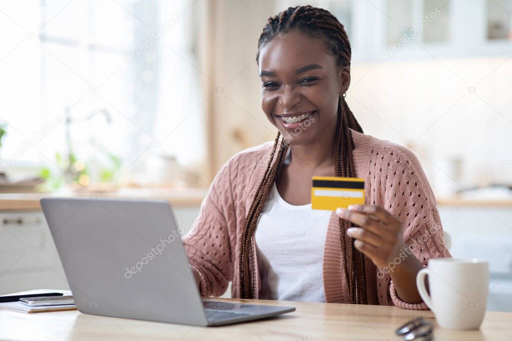 Online Payments. Black Female Holding Credit Card And Using Laptop In Kitchen
