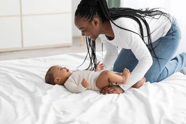 Cute little African American baby lying on bed with mom — Stock Photo, Image