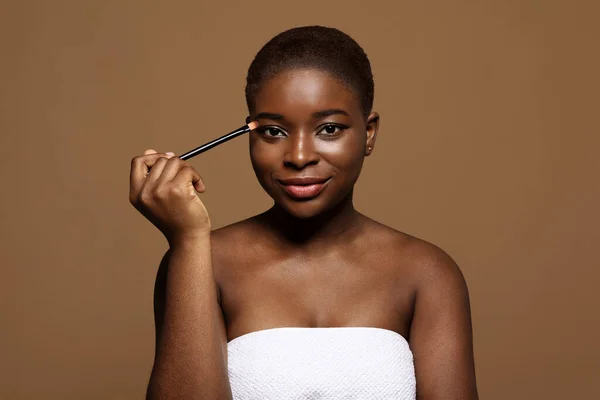 Jovem mulher afro-americana atraente com pele impecável segurando escova de maquiagem — Fotografia de Stock