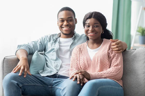 Liebendes schwarzes Paar sitzt auf Sofa im Wohnzimmer — Stockfoto