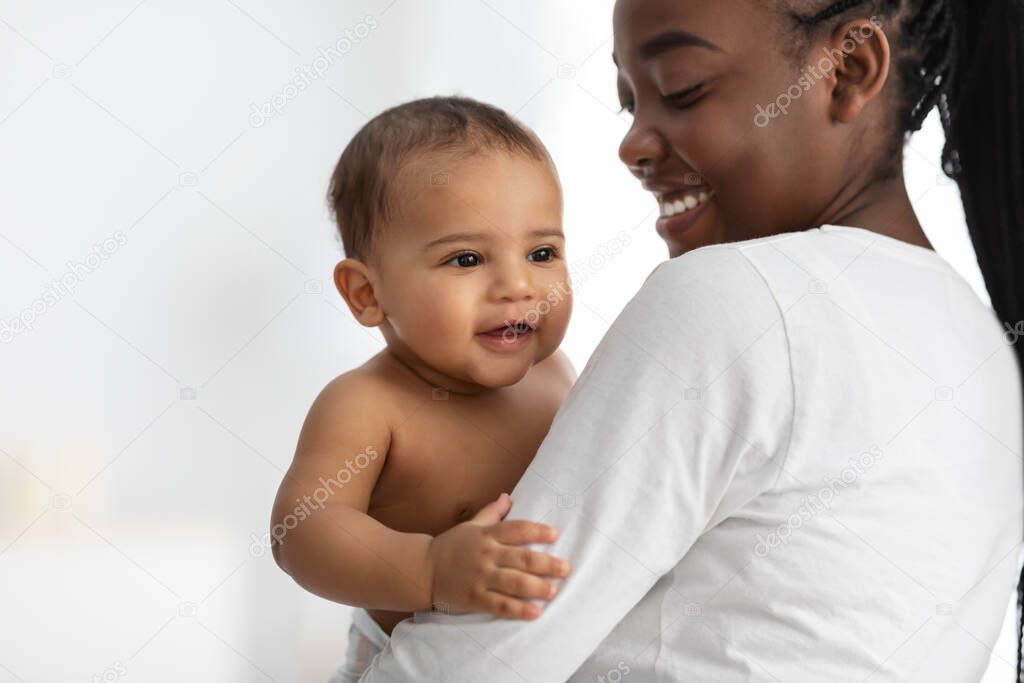 Happy African American mom hugging her cute little child