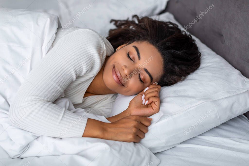 Portrait of young African American woman sleeping in bed