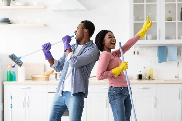 Engraçado casal negro cantando enquanto limpando cozinha — Fotografia de Stock