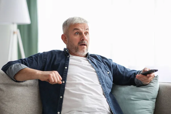 Homem idoso chocado assistindo notícias negativas na TV — Fotografia de Stock