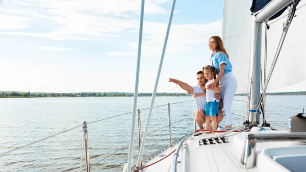 Happy Family Embrasser debout sur le yacht regardant pointant vers l'extérieur — Photo