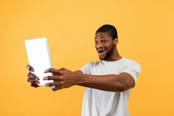 Grande anúncio, oferta e notícias incríveis. Surpreendido afro-americano segurando tablet digital, em pé sobre fundo amarelo — Fotografia de Stock