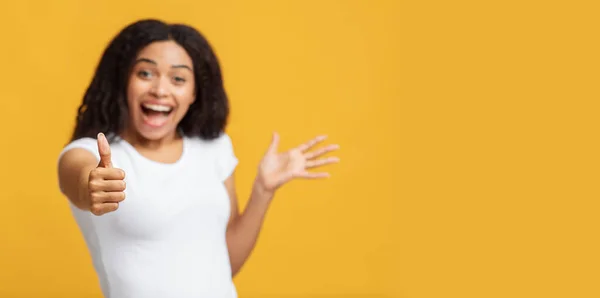 Un geste du pouce levé. Dame afro-américaine ravie montrant comme signe, fond jaune, panorama avec espace libre — Photo