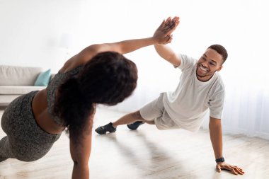 Motive olmuş siyah çift evde çalışırken birbirlerine beşlik çakıyor, tahtada duruyor, takım olarak egzersiz yapıyorlar.