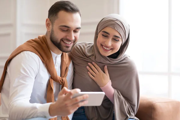 Casal muçulmano alegre usando Smartphone se divertindo juntos em casa — Fotografia de Stock