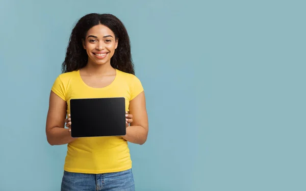 Güzel site. Boş ekranlı tablet gösteren mutlu siyah bayan, mavi stüdyo arka planında duruyor.. — Stok fotoğraf