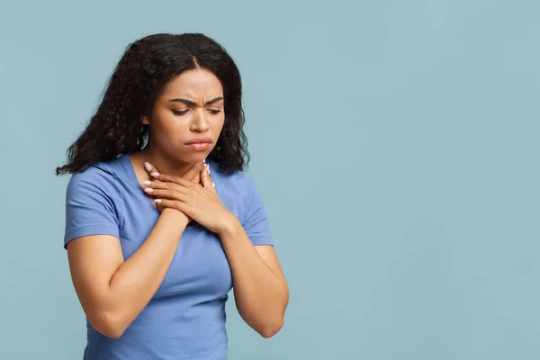 Akut göğüs ağrısı çeken üzgün Afrikalı Amerikalı kadın mavi arka planda kendini kötü hissediyor. — Stok fotoğraf