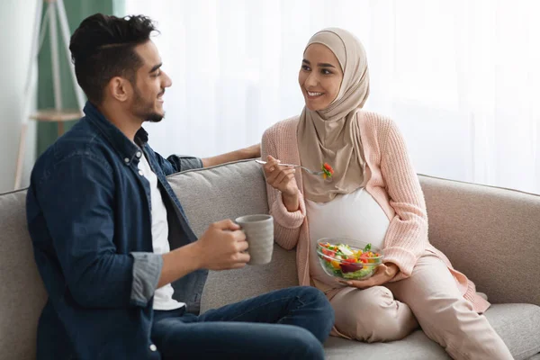 Terhes muszlim hölgy Hidzsábon Zöldségsalátát eszik, míg a férj kávét iszik — Stock Fotó