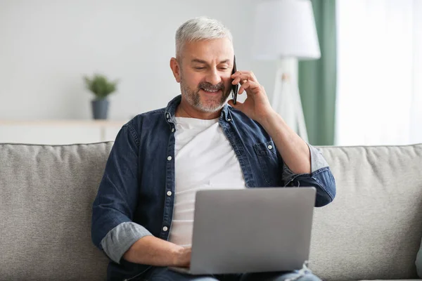 Glada senior man talar i telefon och använder laptop — Stockfoto