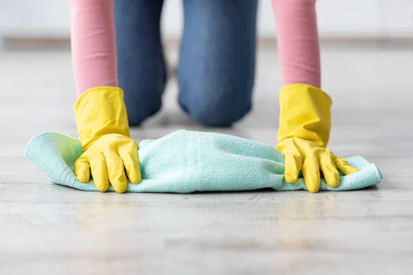 Unrecognizable lady cleaning floor, wearing rubber gloves