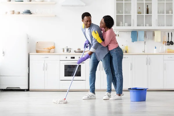 Vreugdevol Afrikaans amerikaans paar schoonmaken huis samen — Stockfoto