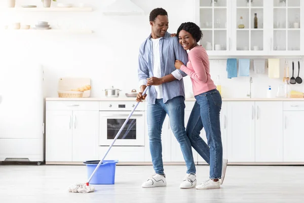 Positivo negro pareja limpieza cocina juntos y abrazos — Foto de Stock