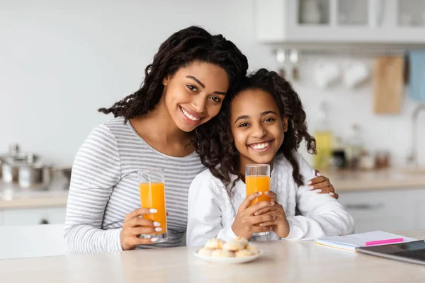 Linda madre negra e hija bebiendo jugo de naranja con galletas — Foto de Stock