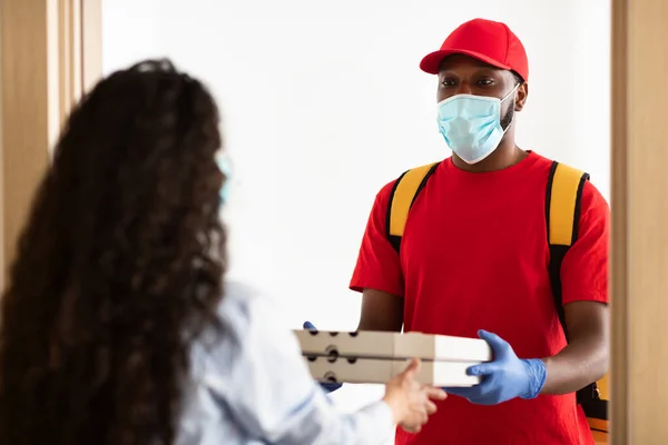 Black delivery man in medical mask holding pizza boxes — Stock Photo, Image