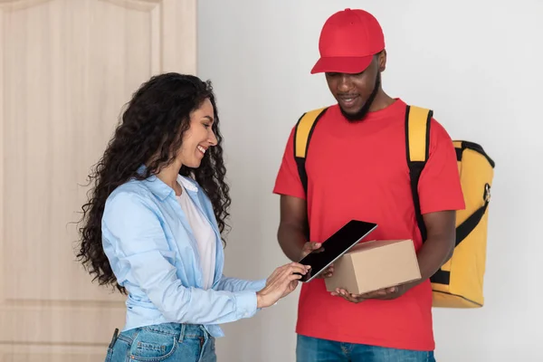 Lächelnde Kundin erhält Bestellung mit digitaler Unterschrift — Stockfoto