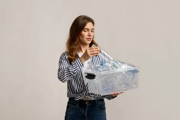 Fiatal gyönyörű nő tesz műanyag palackok konténer a kezében — Stock Fotó