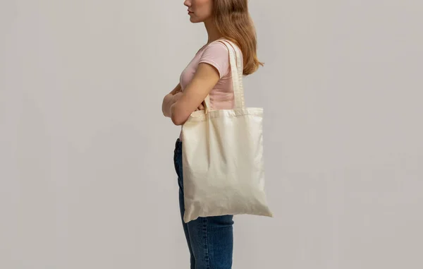 Vista lateral de la foto de la mujer joven que lleva en blanco Eco bolsa de lona —  Fotos de Stock