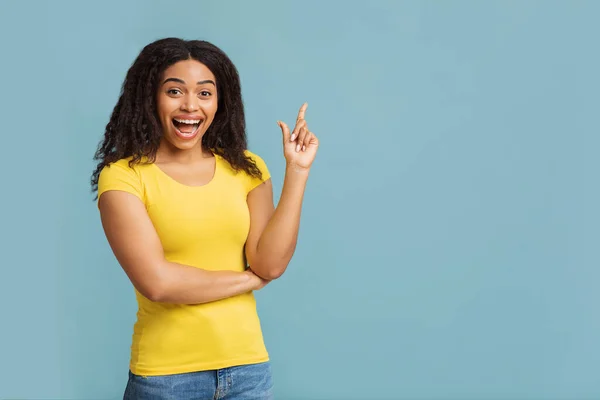Un moment. Femme noire excitée ayant une grande idée, trouver l'inspiration, pointant du doigt sur fond bleu studio — Photo