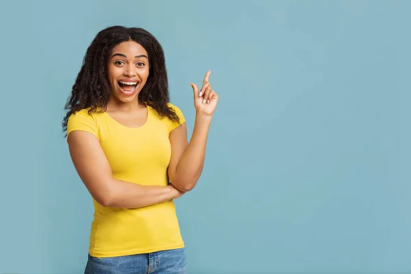 Aha-Moment. Erwähnte schwarze Frau hat eine großartige Idee, findet Inspiration, zeigt mit dem Finger nach oben über blauem Studiohintergrund — Stockfoto