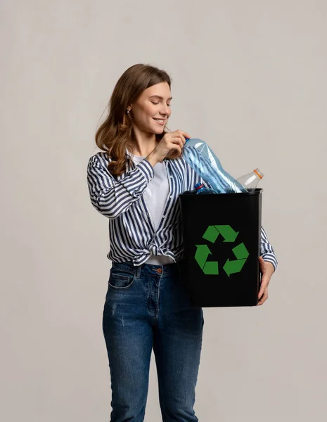 Abfallrecycling-Konzept. Millennial Lady trägt schwarzen Behälter mit leeren Plastikflaschen — Stockfoto