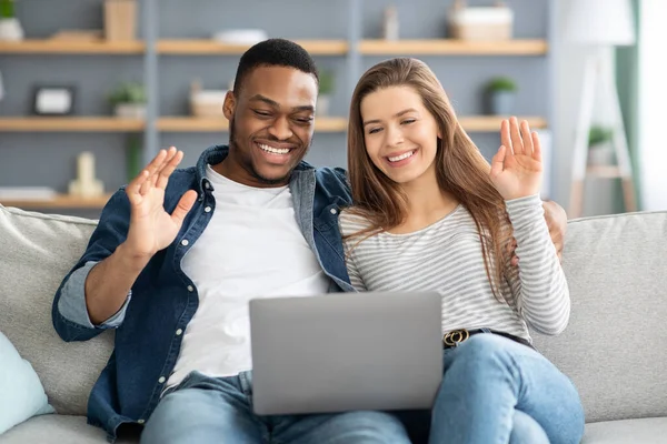 Feliz joven pareja interracial haciendo videollamada en el ordenador portátil en casa — Foto de Stock