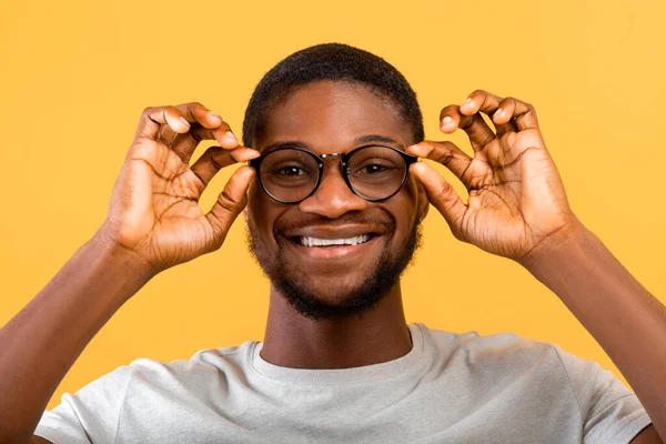 긍정적 인 아프리카 계 미국인 안경을 쓰고 노란 스튜디오 배경에 카메라를 보고 미소짓는 — 스톡 사진