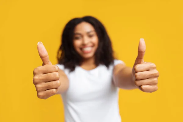 J'aime ça. Heureuse dame afro-américaine geste pouces levés avec les deux mains sur fond jaune, mise au point sélective — Photo