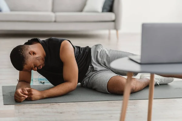 Deportivo hombre negro sentirse mal durante el entrenamiento en línea en casa — Foto de Stock