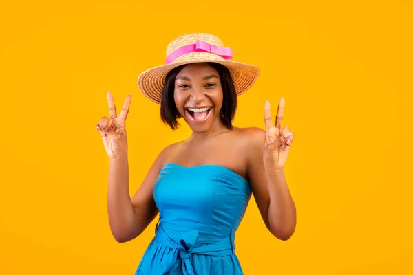 Portrait of excited black woman in trendy summer outfit showing peace gesture with both hands on orange background — Stock Photo, Image