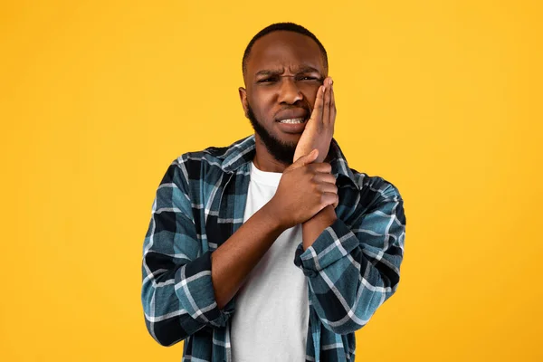 Afroamerikaner mit Zahnschmerzen an der Wange, gelbem Hintergrund — Stockfoto
