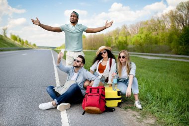 Yol kenarında oturan mutsuz milenyum turistleri, araba yakalayamıyorlar, uzun süre bekliyorlar, akıllı telefon bağlantıları yok.