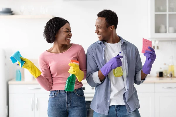 Sorridente coppia nera con forniture per la pulizia posa in cucina — Foto Stock