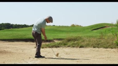 Profesyonel golfçü golf oynuyor, topa vuruyor ve çayırlara vuruyor, yeşil golf sahasında antrenman yapıyor, arkadan bakıyor.
