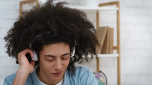 Bushy-Haired Millennial Guy Ouvindo música usando fones de ouvido sem fio dentro de casa — Vídeo de Stock