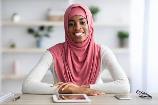 远程职业。Hijab中的黑人女性坐在办公桌前，带着数码桌布 — 图库照片