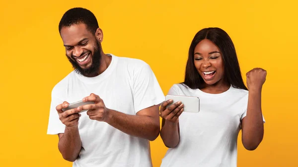 Couple afro-américain à l'aide de téléphones cellulaires, jeu de jeu — Photo