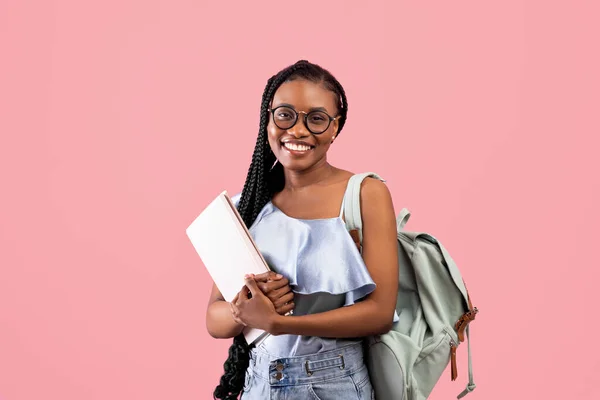 Educazione accademica. Giovane donna nera con zaino e quaderni sorridente alla fotocamera su sfondo rosa studio — Foto Stock