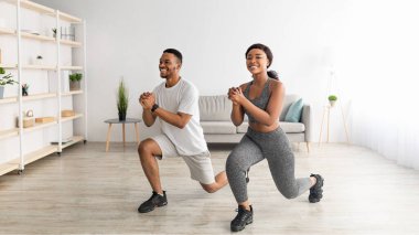 Evde fitness. Tam uzunlukta motivasyonlu siyah çift oturma odasında hamle yapıyor, afiş tasarımı...